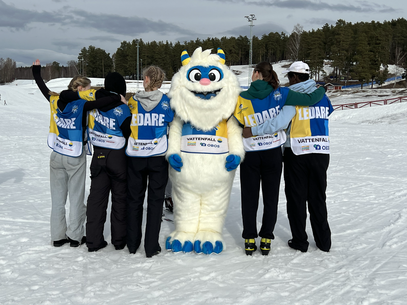 Alla på snö ledare tillsammans med maskoten Flake